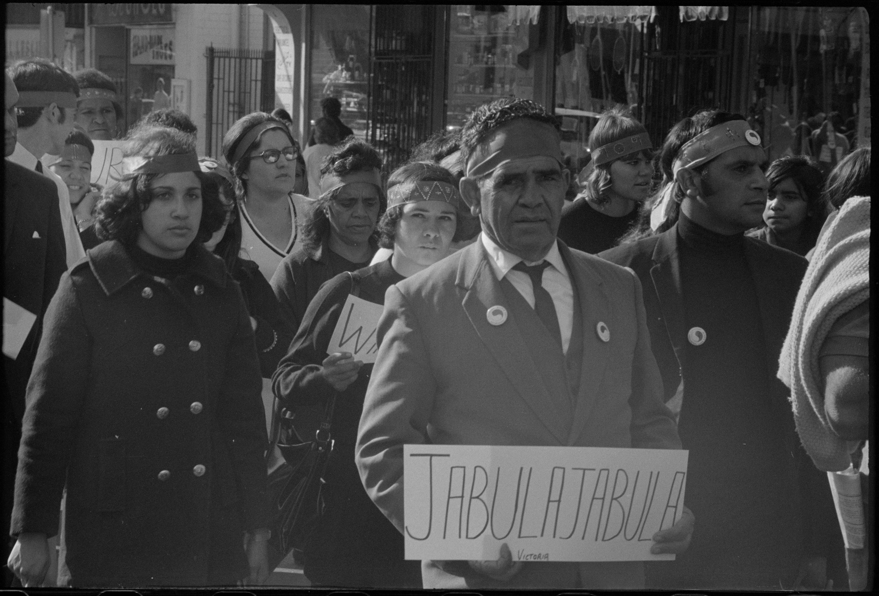 Man walking in protest group holding a placard