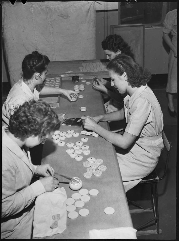 Group of women sit around a table working.